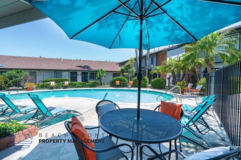 a table with chairs and an umbrella next to a swimming pool